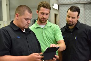 3 men working with a tablet, discussing risk assessments