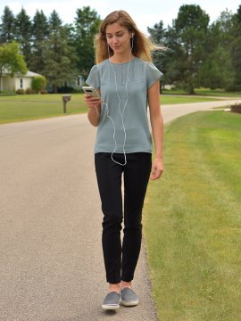 Woman walking while holding phone with headphones on