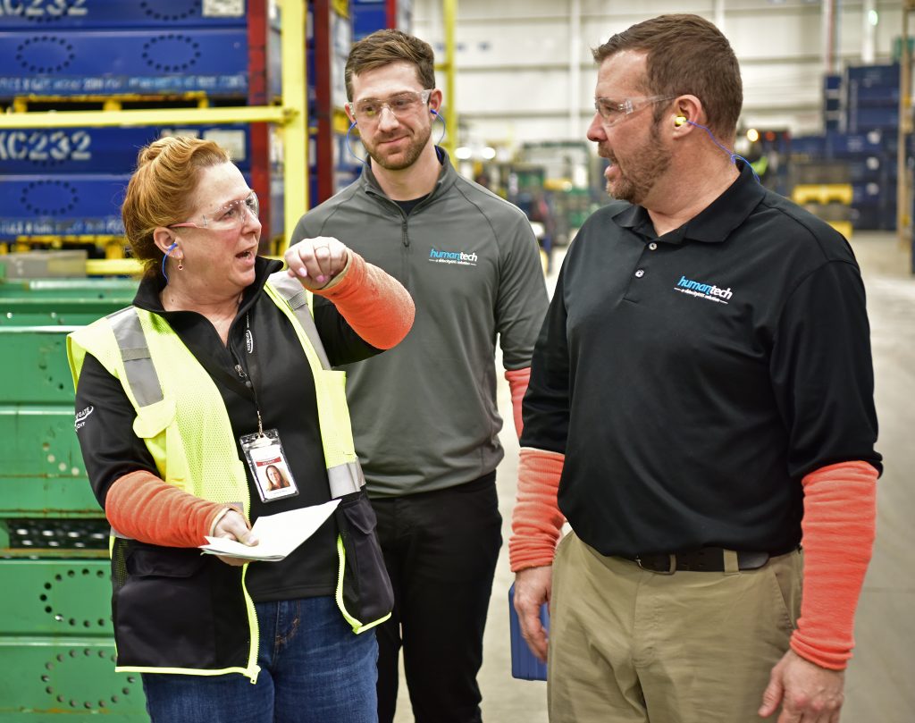 Three people talking on the shop floor in an industrial environment