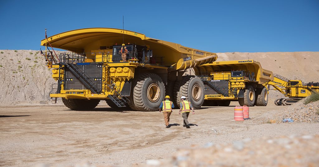 Two Men Walking Towrd Komatsu Mining Machinery